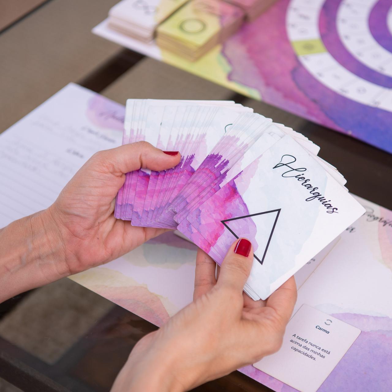 Mãos segurando as cartas das Hierarquias da Jornada Biográfica